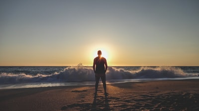 人在黑色衬衫站在海滩日落
